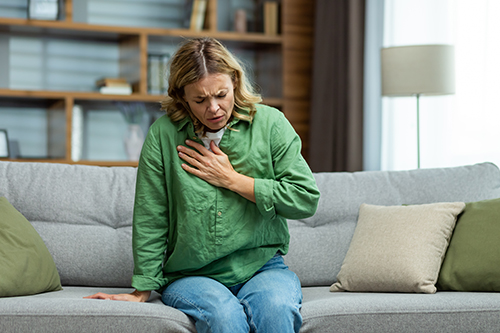 A woman at on a sofa coughing due to serious respiratory infection