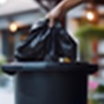 a person placing a trash bag in the trash can outside