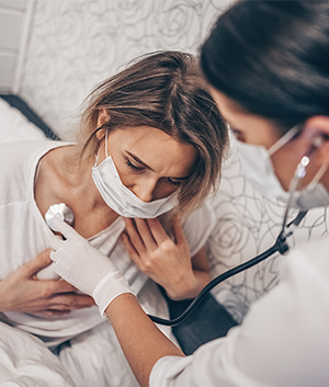 A woman in mask being examined by a doctor