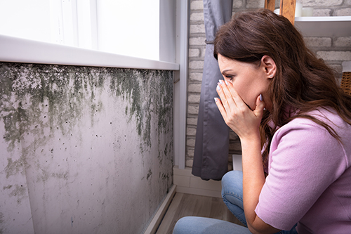 A shocked woman finding mold on her wall