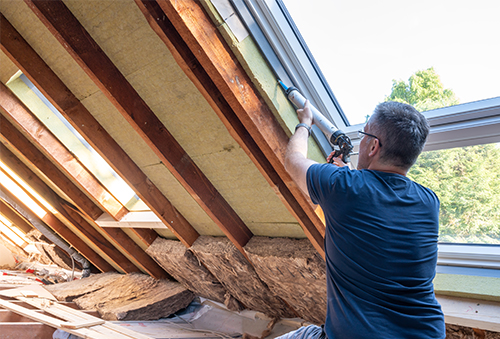 man seals up an attic window to prevent leaks